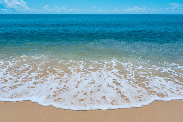 istock blue sea wave on the yellow sand with white bubbles 1392471155