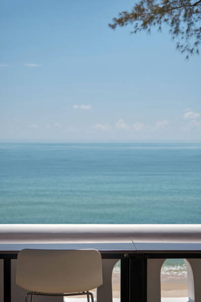 istock vertical frame of blank seaside working space terrace with white bar stool and balcony and blurred blue sea in background 1392471181
