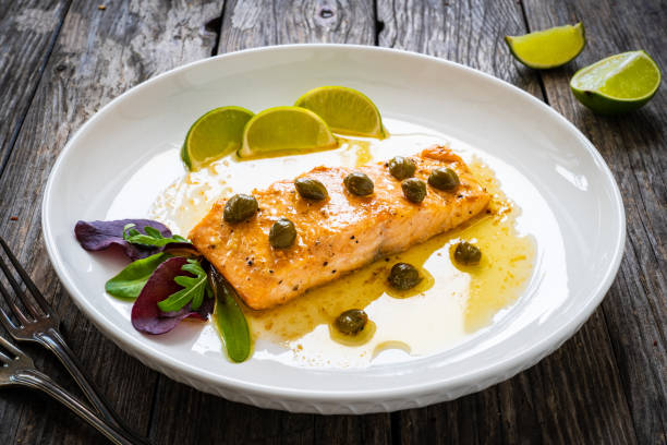 istock Butter sauce fried salmon steak with capers and lime on wooden table 1392471473
