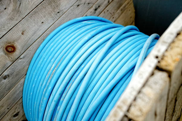 New blue power cable is wound on wooden coil. Background. Cable for laying underground.