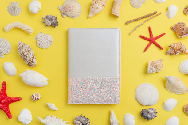 istock Decorative notebook on the table surrounded by shells and starfish with free space to promote the logo or text 1392475623