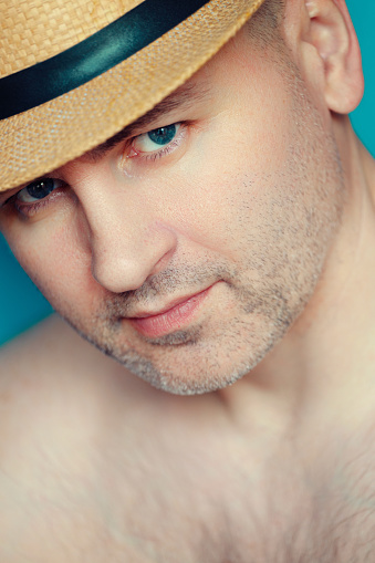 Portrait of white Caucasian man 40-45 years old in hat and bare chest. Seducer and ladies' pleaser. Look from under hat. Man's face with slight unshavenness