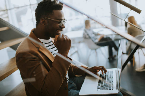 istock Young African American business man working on laptop computer while sitting on a office stairs 1392485338