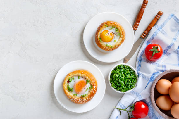 istock Baked buns stuffed with eggs and bacon on plates on a light background. Breakfast eggs. Top view with copy space. 1392486378