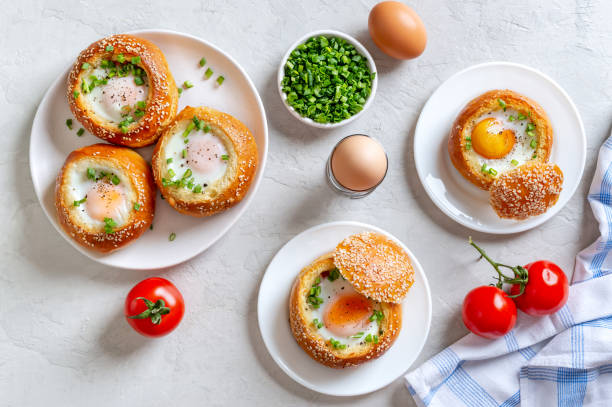 Baked buns stuffed with eggs and bacon on plates on a light background. A la carte breakfast. Top view.