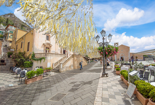 Taormina, Italy - 26 June 2021 - A historical center view of the touristic city in province of Messina, Sicily island, during the summer, famous for Isola Bella sea beach and the old theatre. Here in particular the central street with people