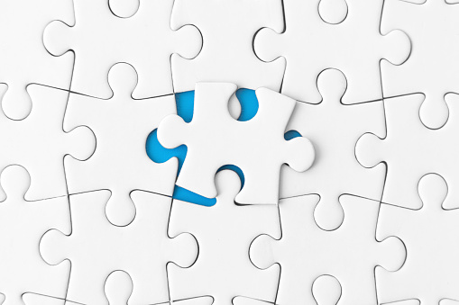 The missing puzzle piece lies against the blue background of the white puzzle. Jigsaw puzzle concept