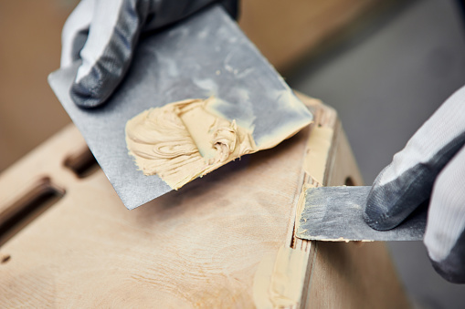 Masilla de madera. Trabajador manual empacando productos de madera en la fabricación de carpintería. Primer plano del proceso de trabajo photo