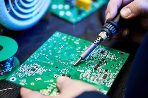 Engineer is soldering a computer board, circuit, chip or microchip. Repairing Hardware Equipment. Repair Shop and Worker with Tools. Testing Modern Digital Device on Desk . Electronic Devices Concept el ingeniero está soldando una placa de computadora, circuito, chip o microchip. reparación de equipos de hardware. taller de reparación y trabajador con herramientas. probando el dispositivo digital moderno en el escritorio. concepto de dispositivos el