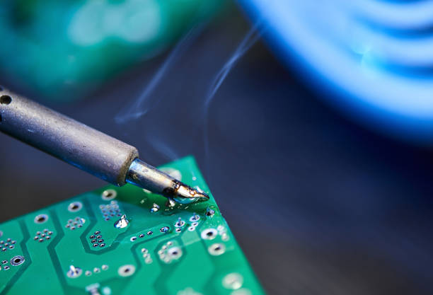 istock Engineer is soldering a computer board, circuit, chip or microchip. Repairing Hardware Equipment. Repair Shop and Worker with Tools. Testing Modern Digital Device on Desk . Electronic Devices Concept 1392494481