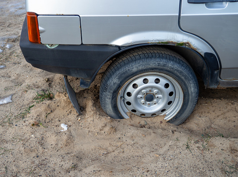 the wheel of the car is stuck in the sand. Stuck tires. Bad ecology