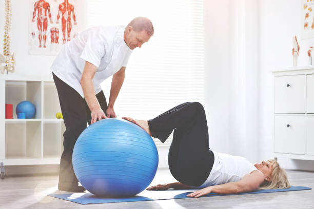 istock Shot of a physiotherapist helping a client stretching using a medicine ball 1392499331