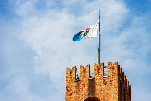 Close-up of the ancient medieval Civic Tower in Treviso Downtown, 1218, with the flag of the city. Town square called Piazza dei Signori, Veneto, Italy, Europe.