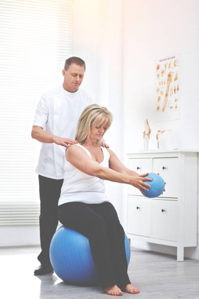 istock Shot of a physiotherapist helping a client stretching using a medicine ball 1392499462