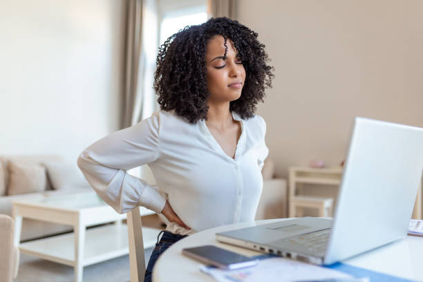 Back Pain Bad Posture Woman Sitting In Office. Young afro woman suffering from back pain while working on laptop at home Back Pain Bad Posture Woman Sitting In Office. Young afro woman suffering from back pain while working on laptop at home bad posture stock pictures, royalty-free photos & images