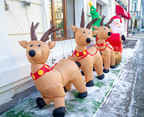 Inflatable Santa Claus and reindeer on the street. Christmas design. New Year's decoration on the street. The atmosphere of the holiday. Winter frosty street\