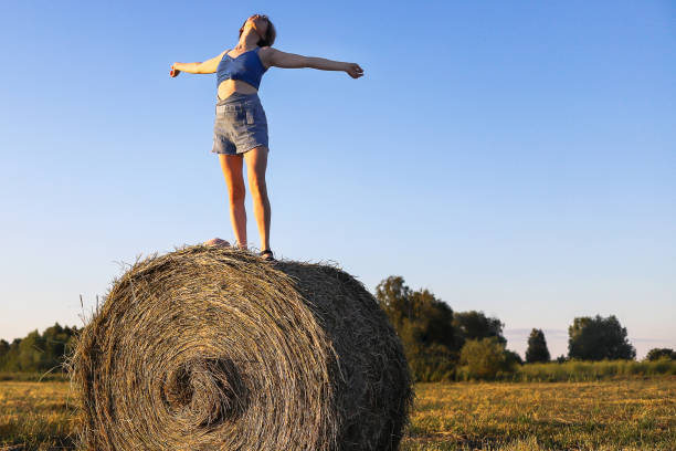 istock Girl resting on a haystack in an open field 1392508402