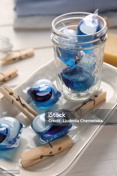 Many Wooden Clothespins And Laundry Detergent Pods On White Table Stock Photo - Download Image Now