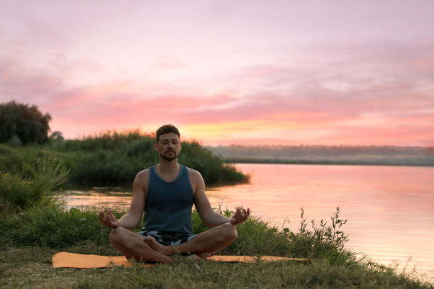 istock Man meditating near river in twilight. Space for text 1392510387