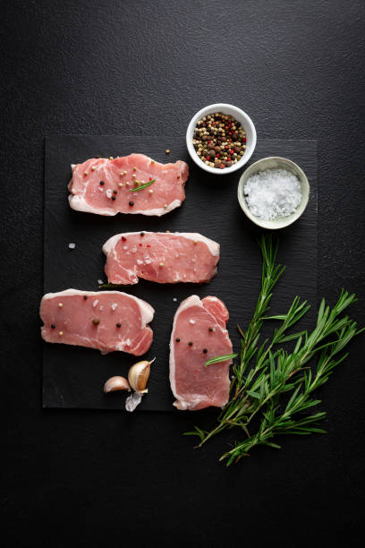 Raw uncooked meat slice on slate and spice rosemary top view stock photo
