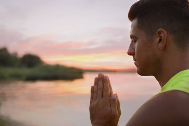 istock Man meditating near river at sunset. Space for text 1392511073