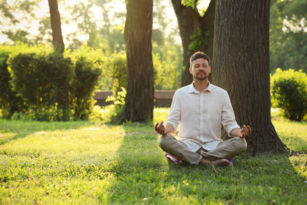 istock Man meditating in park on sunny summer day. Space for text 1392511076