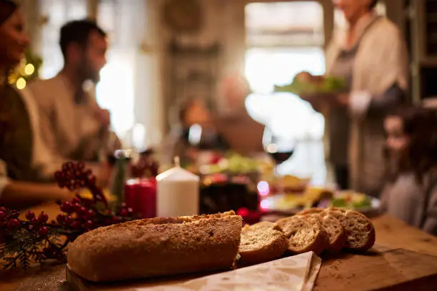 Close up of slices of baguette on dining table with people in the background.