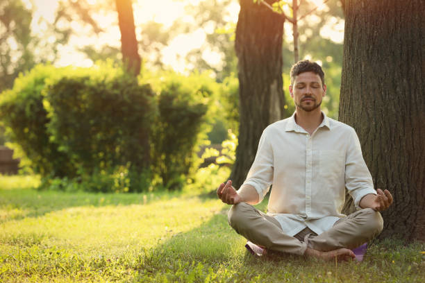 istock Man meditating in park on sunny summer day. Space for text 1392511390
