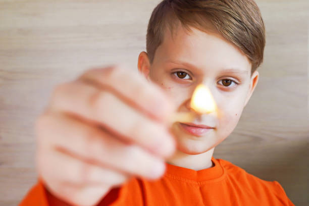 A child boy holding a lighted match in his hands is very dangerous.