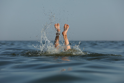 Drowning woman's legs sticking out of sea
