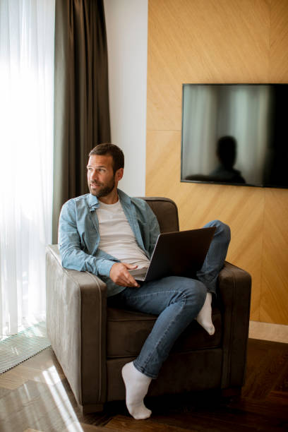 istock Young man using laptop in the living room 1392515049