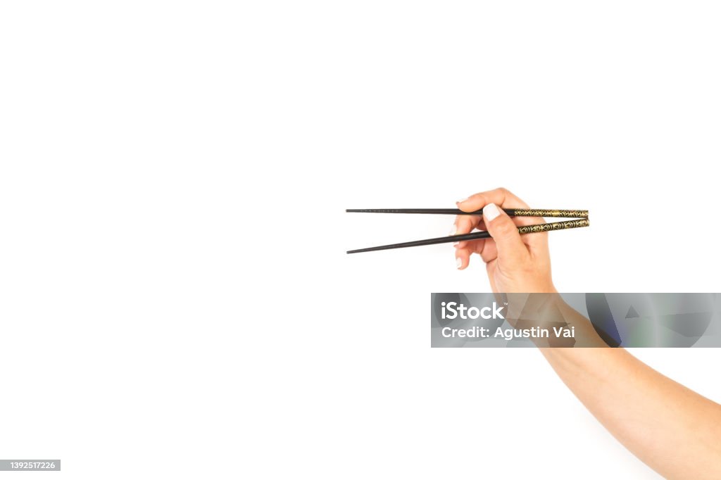 Woman hand holding chopsticks on a white background Woman hand holding chopsticks on a white background with copy space Chopsticks Stock Photo