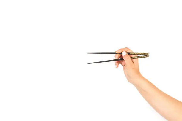Woman hand holding chopsticks on a white background with copy space