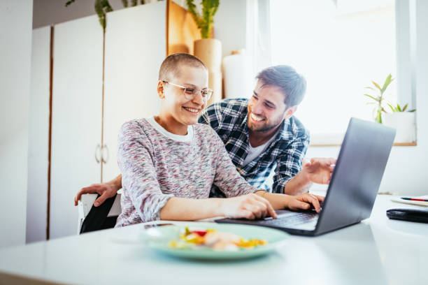 Day in a life of female cancer patient - woman working from home on laptop stock photo