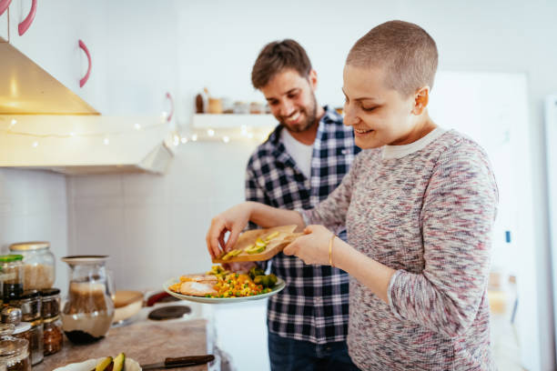 Day in a life of female cancer patient - couple cooking healthy food at home stock photo