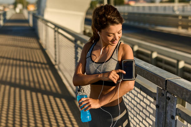 istock Female runner adjusting music on mobile phone before jogging 1392517926
