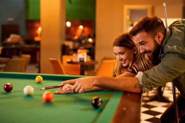 istock Young happy couple enjoying playing billiard on a date in pool hall 1392519903