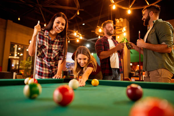 istock Group of friends having fun while playing pool in a local pool hall 1392521233