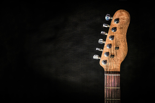 Close-up macro of a guitar string on a tuning peg on the fretboard.