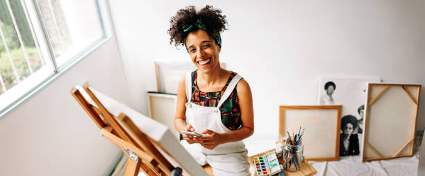 istock Cheerful painter holding a smartphone in her art studio 1392525165