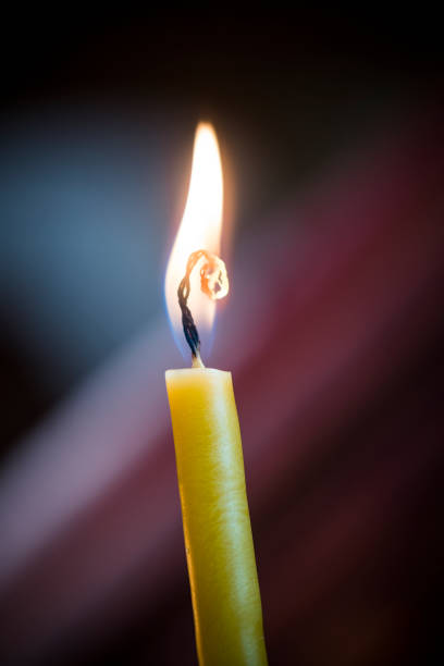 istock Yellow candle flickering against dark background 1392527176