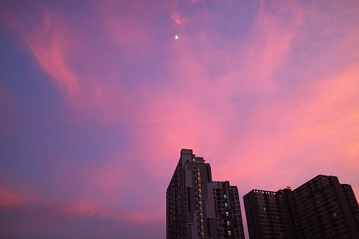 Romantic sunset sky over the city with a bright quarter moon