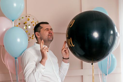 Expectant father is having a gender reveal party.Man holds a black balloon with the inscription Boy and Girl.Family,pregnancy and prenatal care concept.