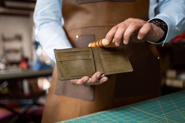 istock Unrecognizable male tailor with a work tool smooth the edges on wallet 1392530191