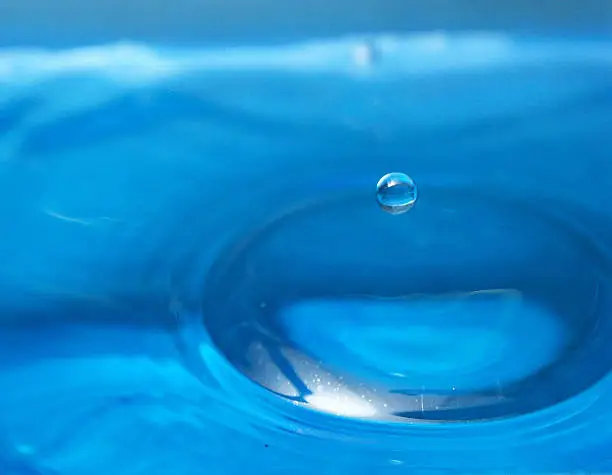 Dripping, blue drop caught in the air.