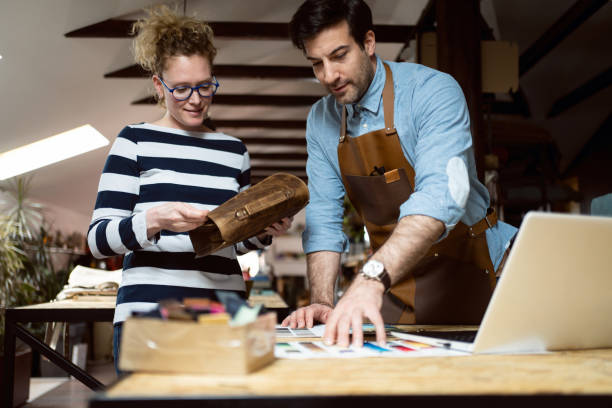 istock Tailor showing to a female customer, material and accessory for a bag 1392530810