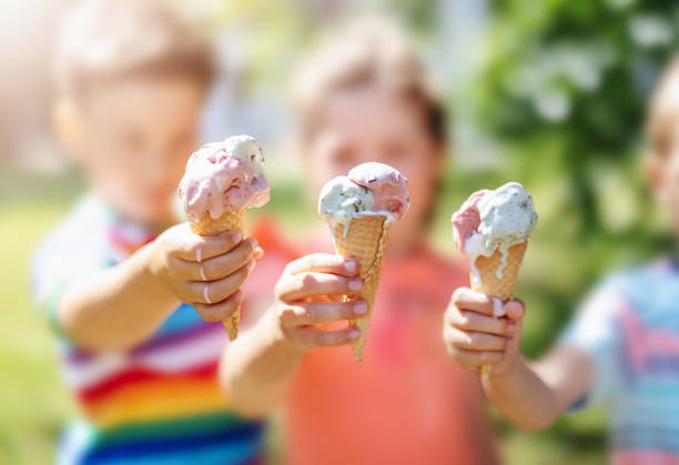 grupo de niños en el parque comiendo helado frío. - polo comida dulce congelada fotografías e imágenes de stock