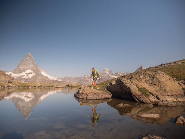istock Man jumps from rock to rock on alpine lake 1392538253