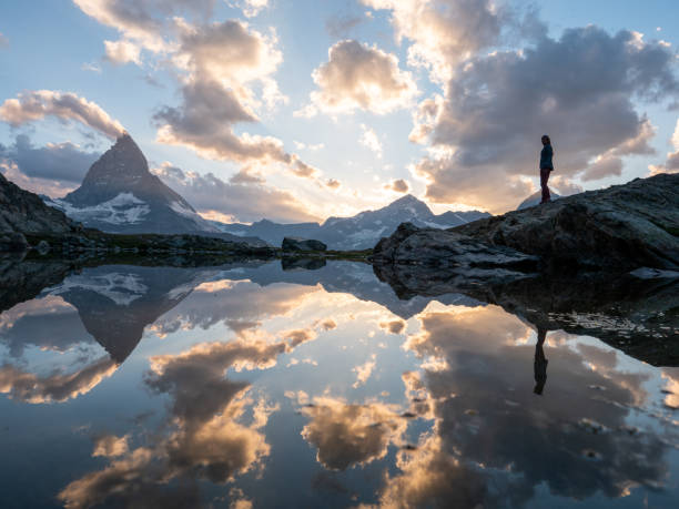 女性は湖畔でリラックスし、日没時にマッターホルン山を熟考する - matterhorn swiss culture european alps mountain ストックフォトと画像