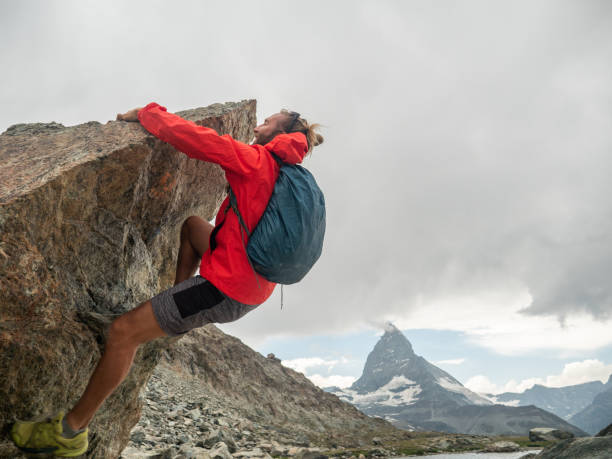 istock Sporty man climbing boulder, Matterhorn in distance 1392541433